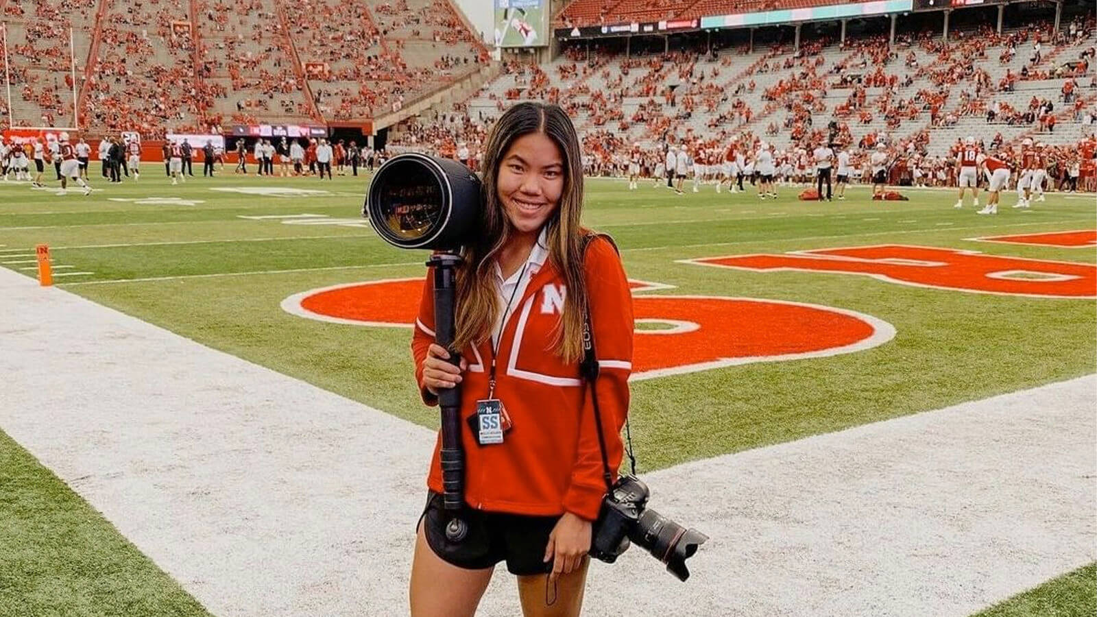 Student holding camera on field at Memorial Stadium