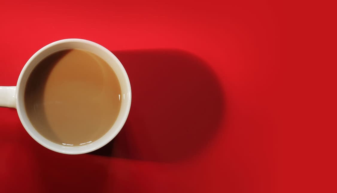 An overhead view of a cup of coffee on a red background