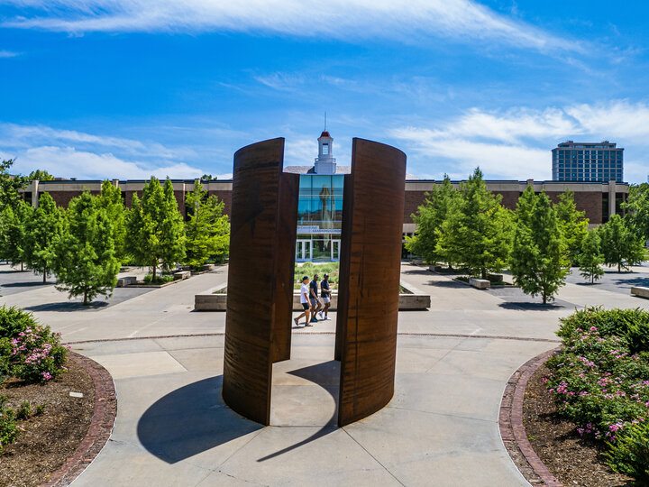 Students walk by Greenpoint sculpture by Richard Serra outside Love Library on a sunny day.