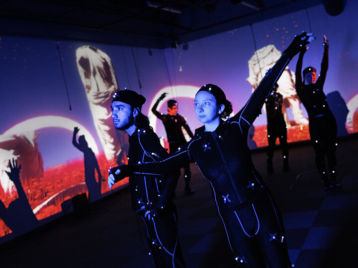 Isaiah Griffith and Marley Hewitt, second-year students in the Carson Emerging Media Arts program, pose in Mo-Cap (motion capture) suits with a group of students being filmed.