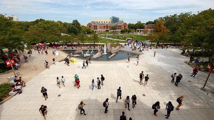 The green space fountain on a sunny day busy with people everywhere.