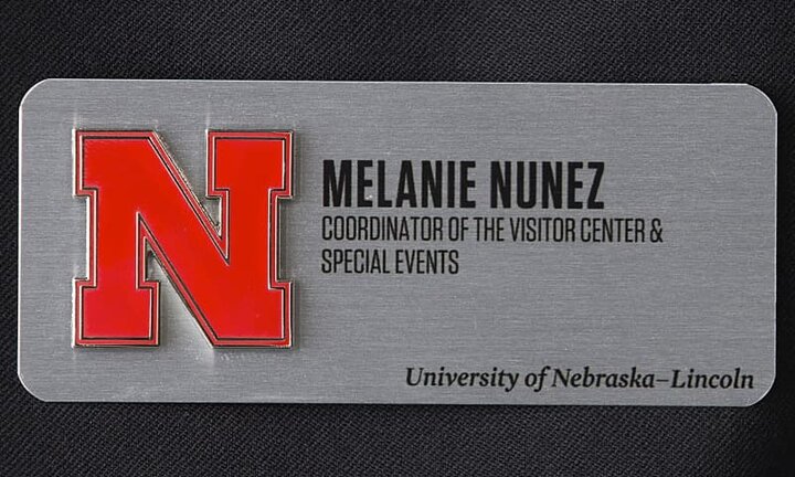 Silver nametag with red N logo on black cloth