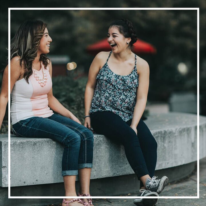 two women sitting and talking with white frame